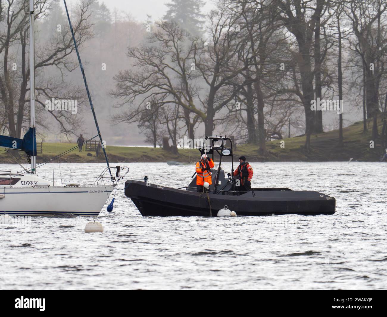 Lake Wardens bringt ein Segelboot wieder an, das durch Sturmwinde am Lake Windermere in Ambleside, Lake District, Großbritannien von seinen Anlegestellen gerissen worden war. Stockfoto