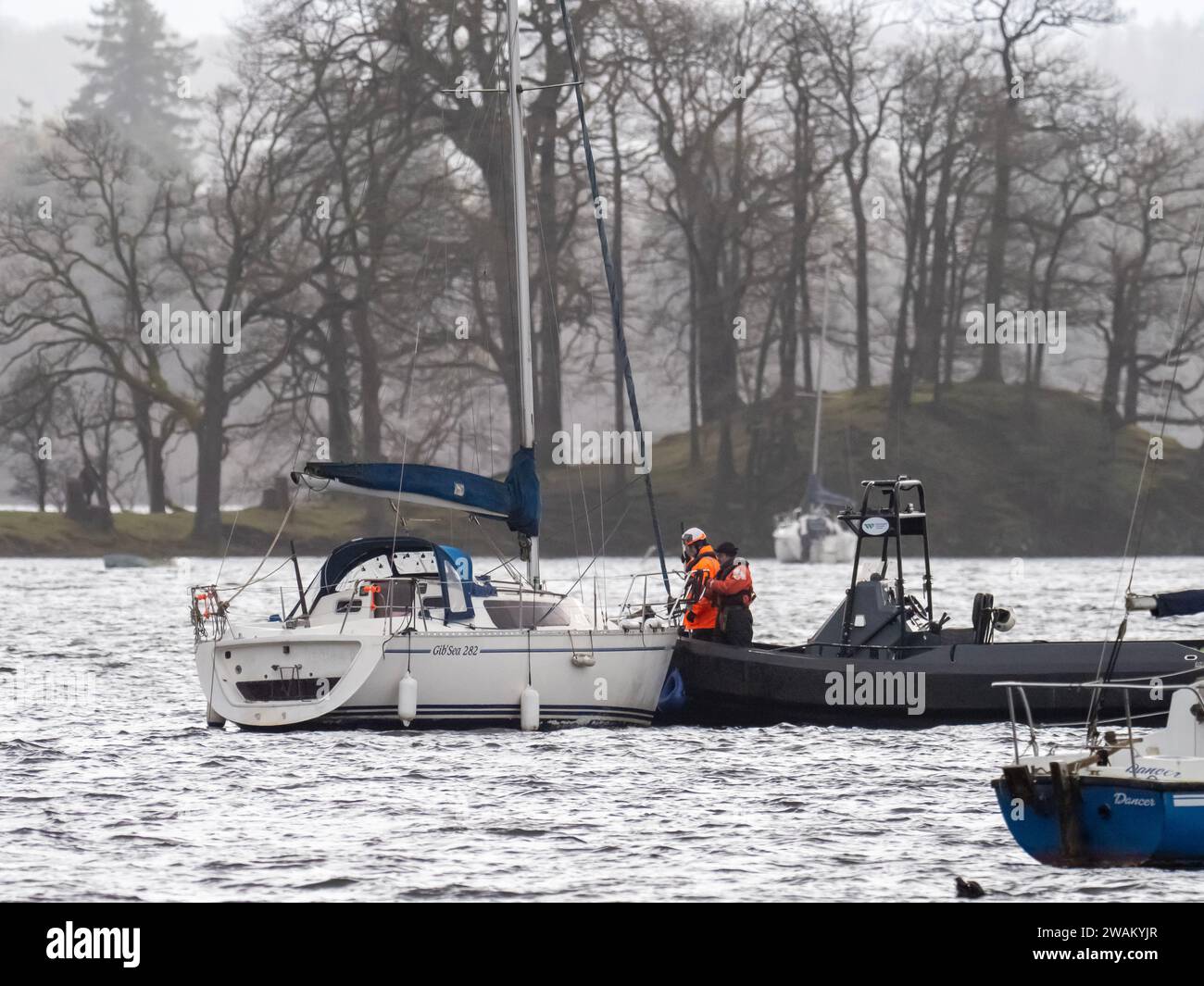 Lake Wardens bringt ein Segelboot wieder an, das durch Sturmwinde am Lake Windermere in Ambleside, Lake District, Großbritannien von seinen Anlegestellen gerissen worden war. Stockfoto
