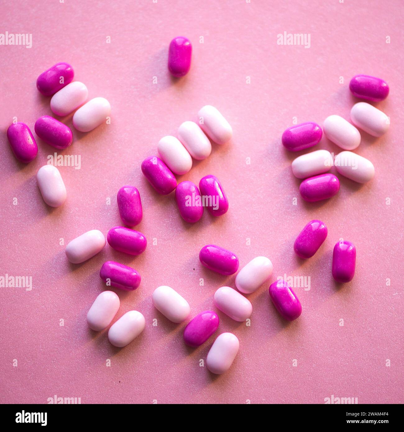 Ein Haufen rosafarbener und weißer Drogen in Form eines Herzens auf rosa Hintergrund Stockfoto