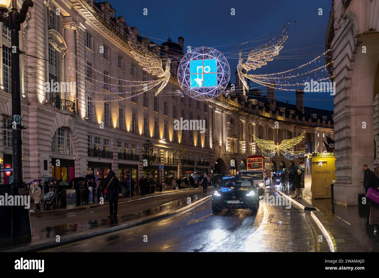 London, Großbritannien - 7. Dezember 2023: Regent Street im Zentrum von London mit Weihnachtsbeleuchtung. Die Leute sind Weihnachtseinkäufe und drei rote Londoner Busse Stockfoto