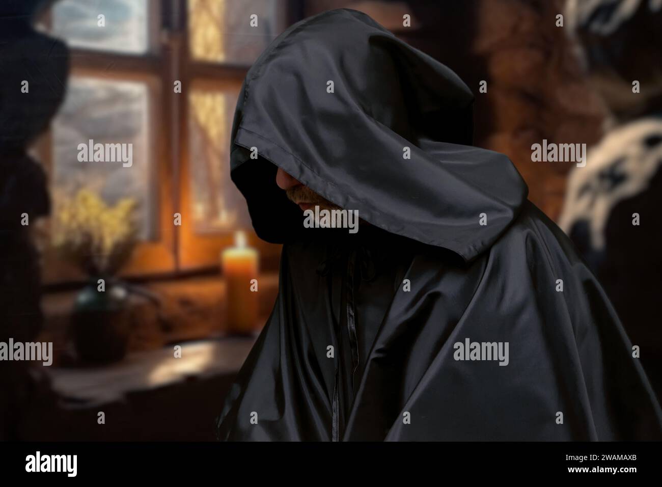 Ein älterer Mönch in schwarzer Cassocke betet in einer Zelle vor einem Fenster mit einer Kerze. Stockfoto Ein älterer Mönch in schwarzer Cassocke betet in einer Zelle vor einem Fenster mit einer Kerze. Stockfoto