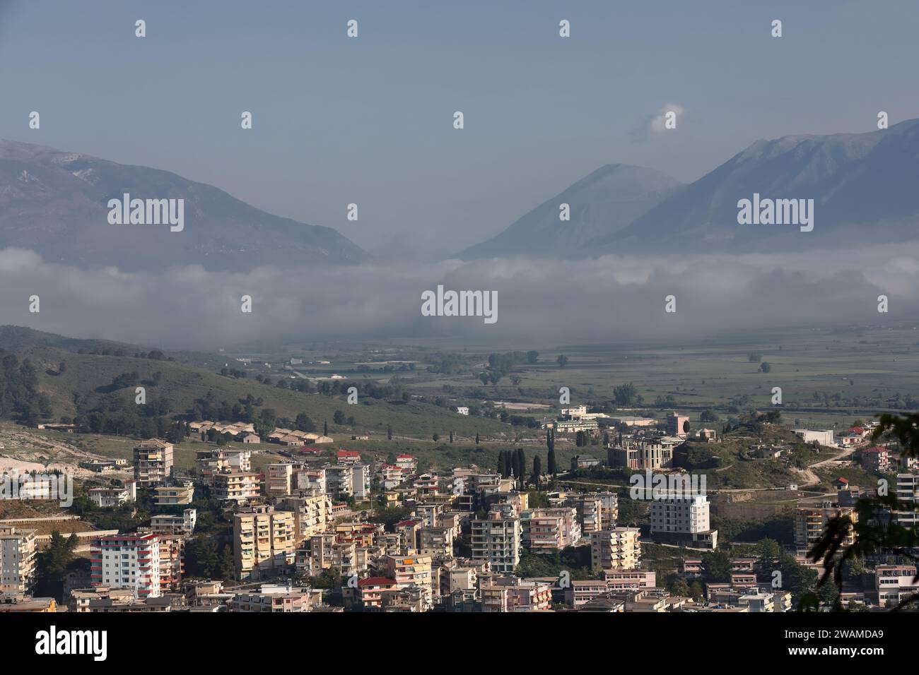 195 Panoramablick auf die unteren Gebäude am Hang des Massivs Mali i i Gjere, nebelbedecktes Tal des Drino Flusses. Gjirokaster-Albanien. Stockfoto