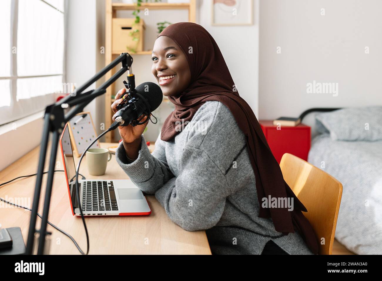 Junge afrikanische muslime, die Podcast mit Mikrofon in ihrem Zimmer aufnimmt Stockfoto