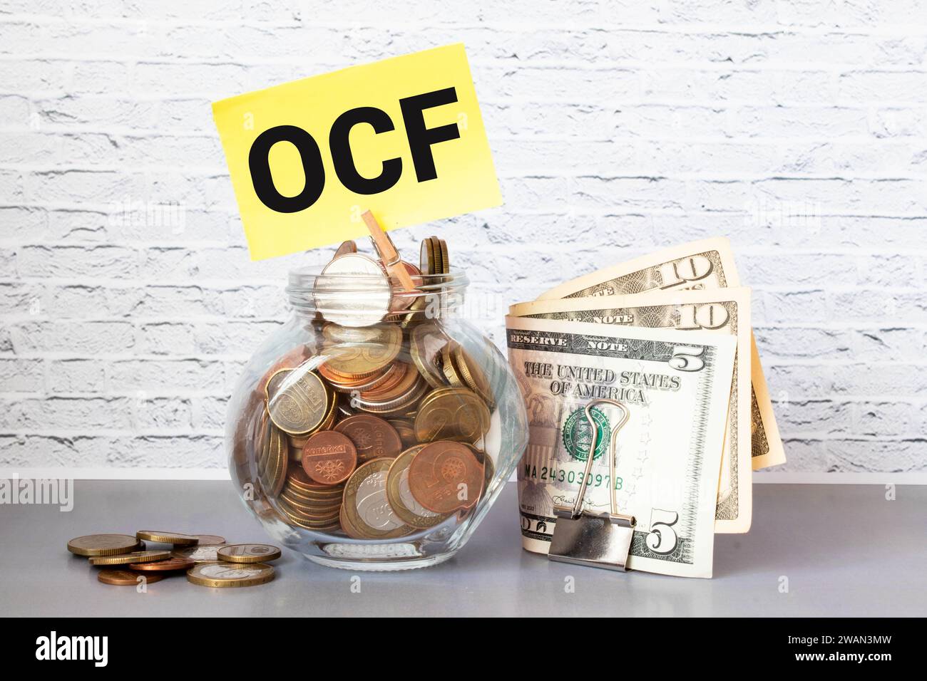 Der Text OCF - Operating Cash Flow - ist auf drei Holzwürfeln geschrieben, die auf einem weißen Tisch stehen. Im Hintergrund - ein Berg aus Holzwürfeln mit Lette Stockfoto