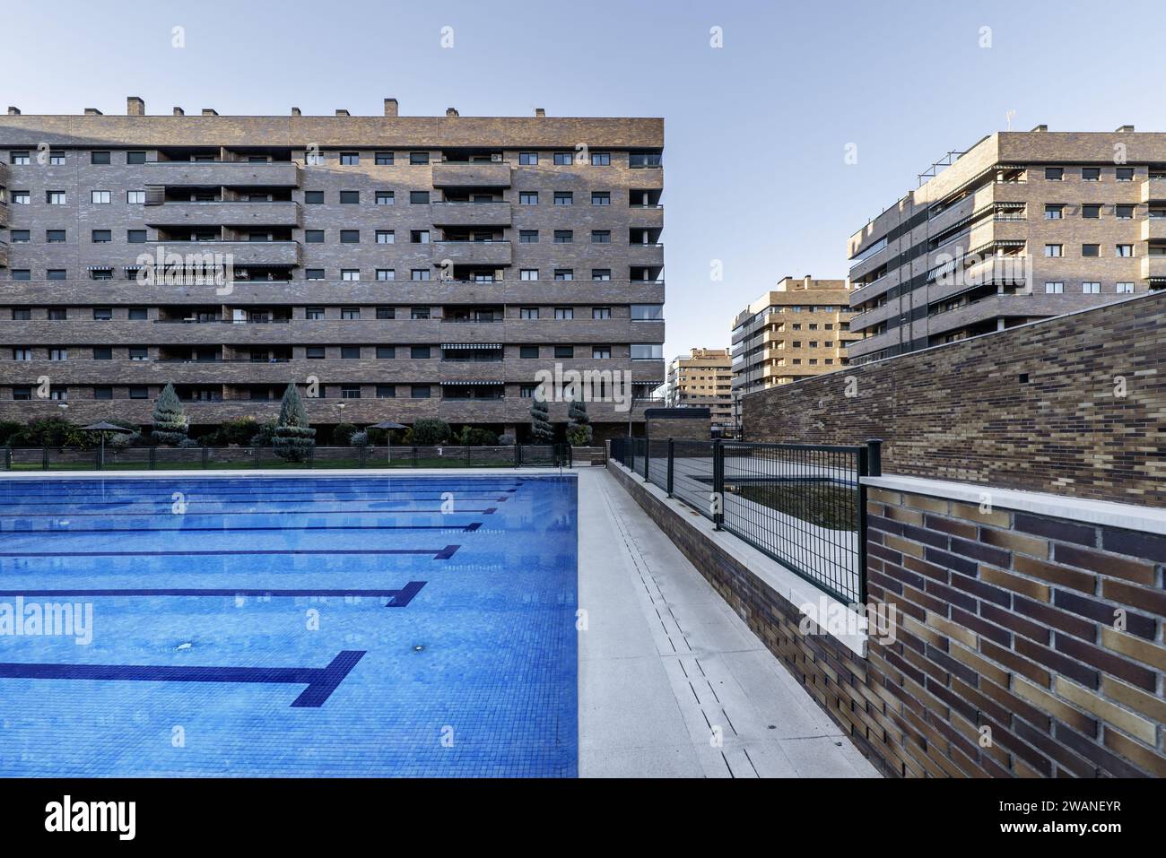 Ein großer Swimmingpool in der Mitte der Gemeinschaftsbereiche einer Wohnsiedlung, gebaut mit dekorativen braunen Ziegeln Stockfoto