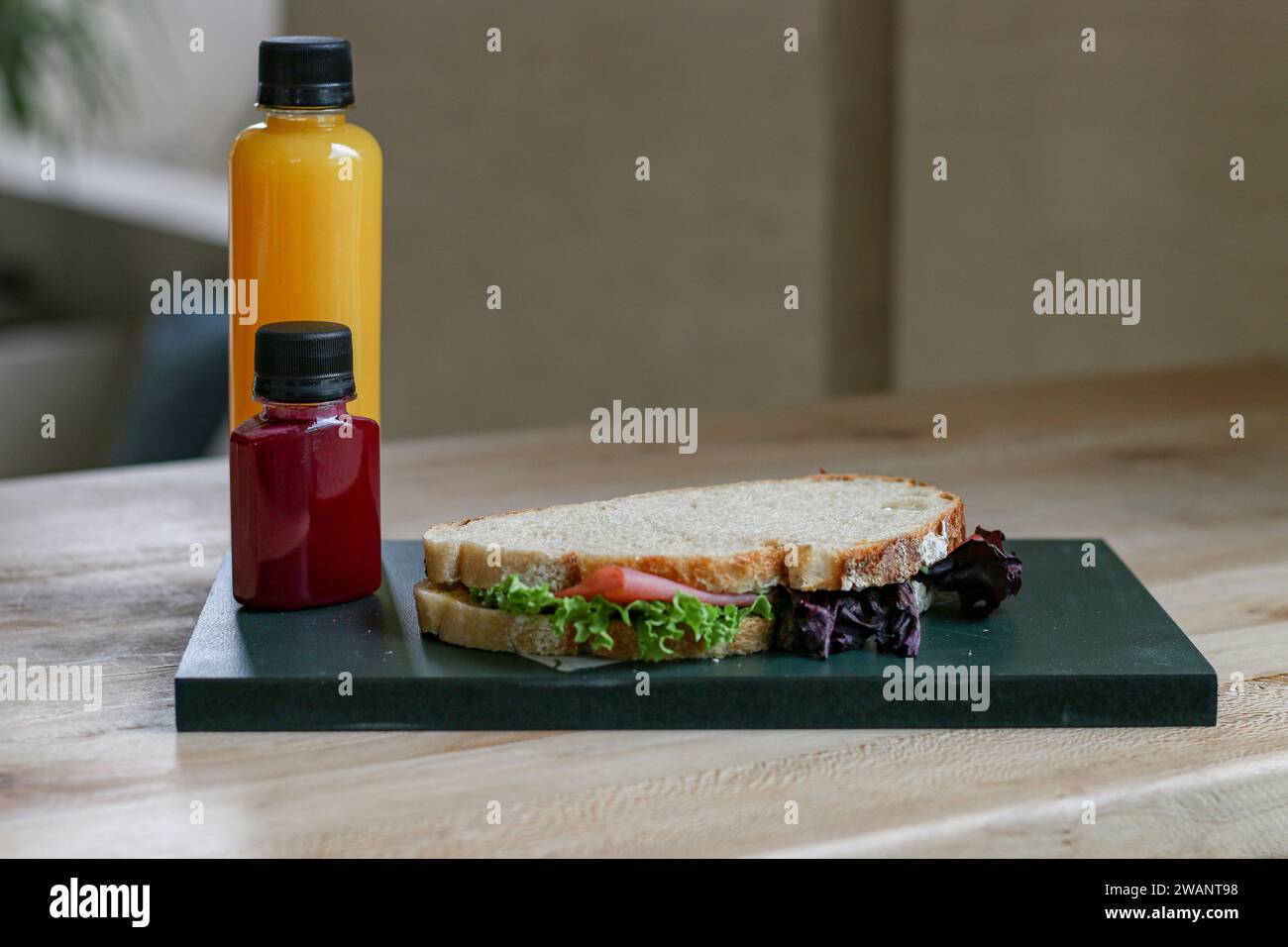 Hamburger mit Salat und Käse auf Holzbrett mit Saftflasche auf dem Tisch Stockfoto