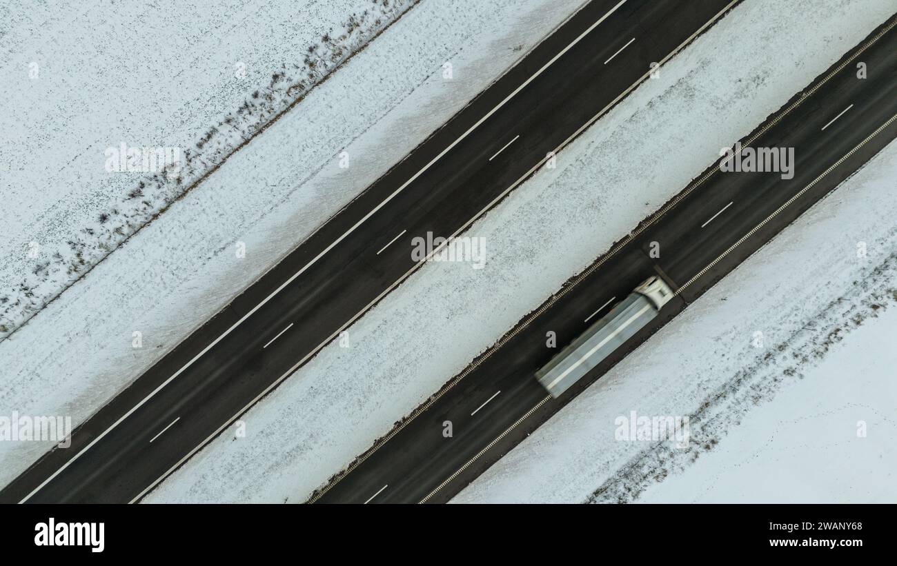 Drohnenfotografie der Landstraße von oben nach unten während des bewölkten Wintertages Stockfoto