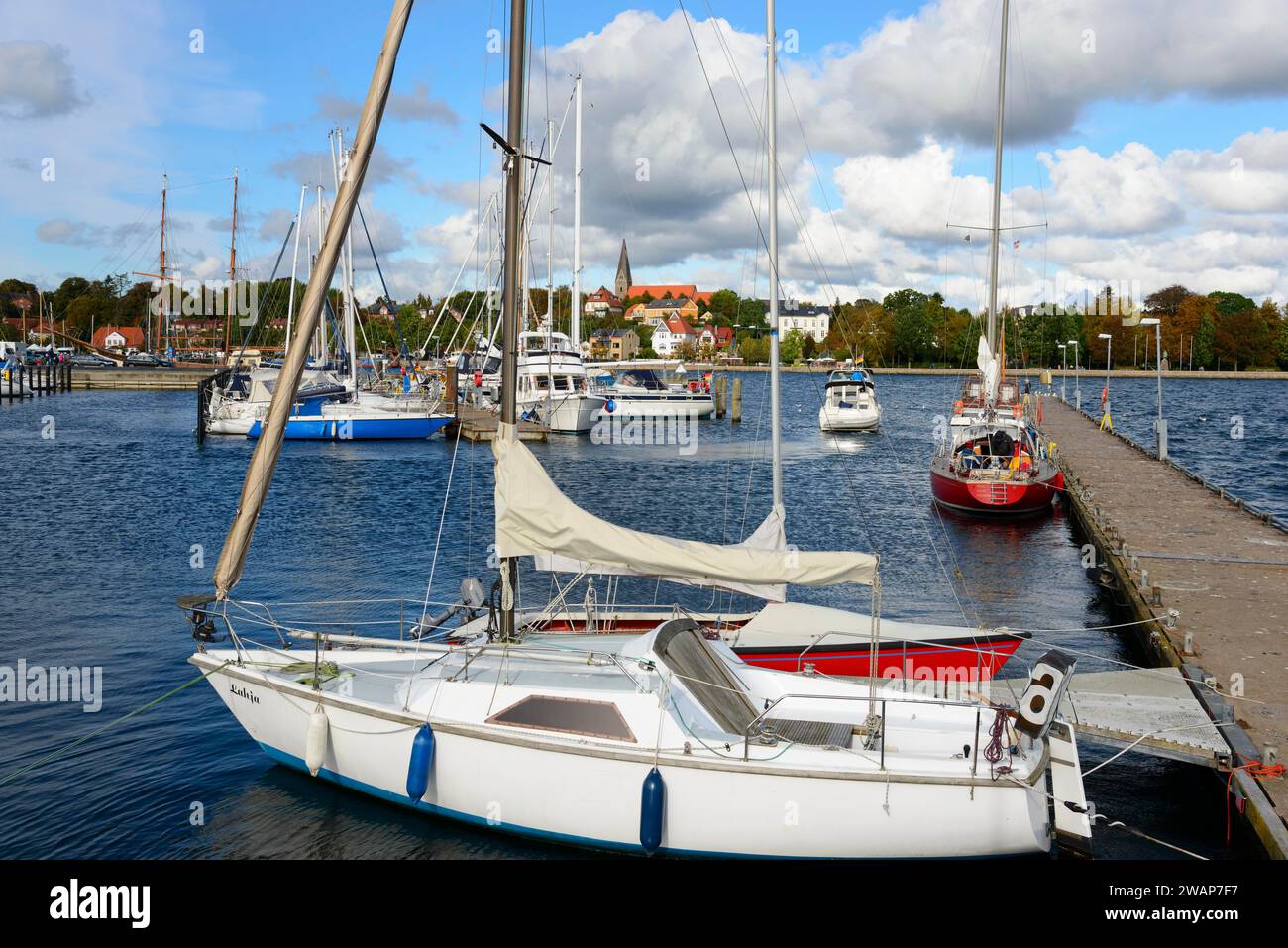 Segelboote liegen im ruhigen Wasser eines Yachthafens, mit Blick auf die Stadt und bewölktem Himmel im Hintergrund, Eckernförde, Schleswig-Holstein, Deutschland, Europa Stockfoto