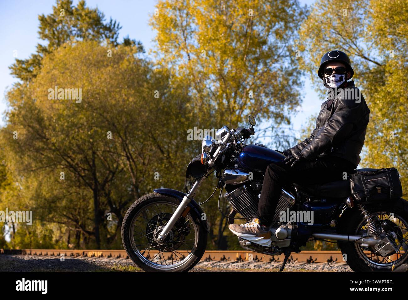 Motorradfahrer in Lederjacke und Helm auf einem Vintage-Motorrad in der Natur. Das Konzept des Motorradlebens und der Saisonbeginn Stockfoto