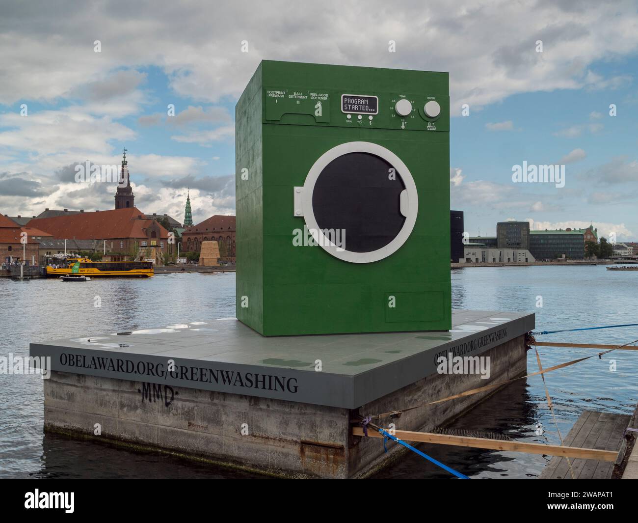 Eine riesige grüne Waschmaschine beim Maststudio, die die Praxis des Grünwaschens karikiert, schwimmt auf einem Lastkahn in Kopenhagen, Dänemark. Stockfoto