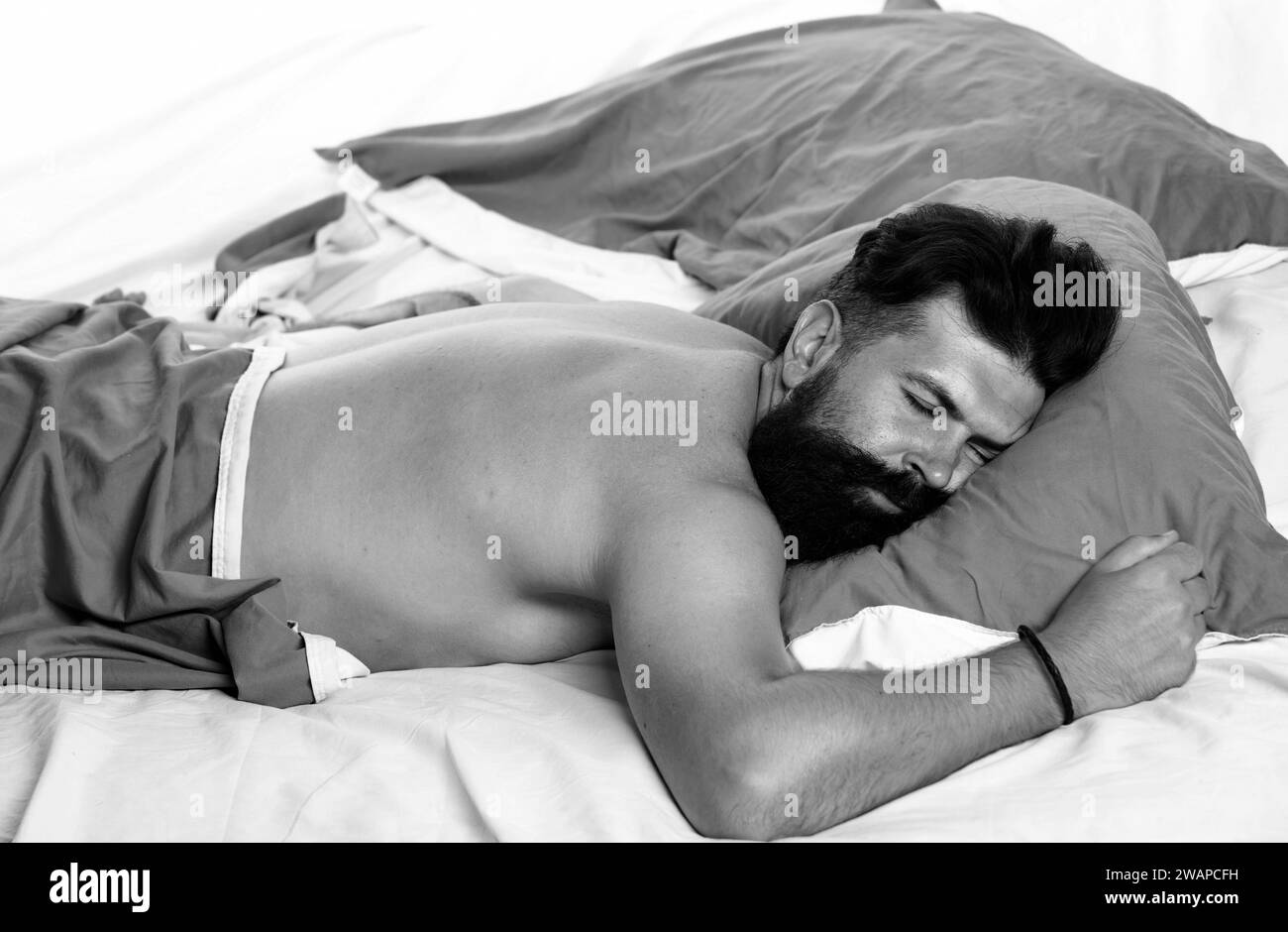 Mann schläft auf dem Bett mit sehr tiefen Schlaf. Junger Mann schläft auf dem Bett. Junger Mann im Bett - versucht zu schlafen. Stockfoto