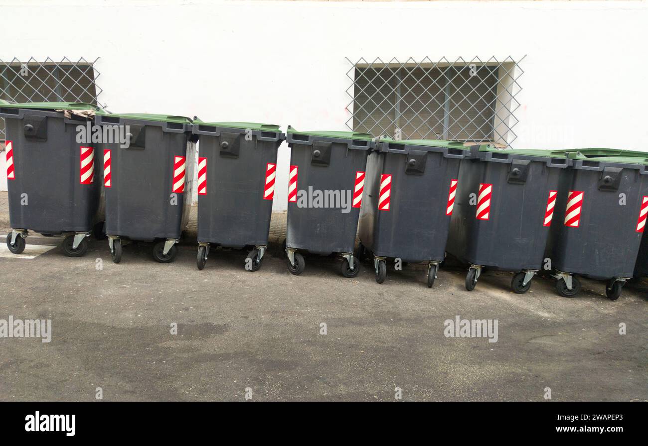 Linie von grauen Müllcontainern, die an Hanglagen abbremsen. Städtischer Hintergrund Stockfoto