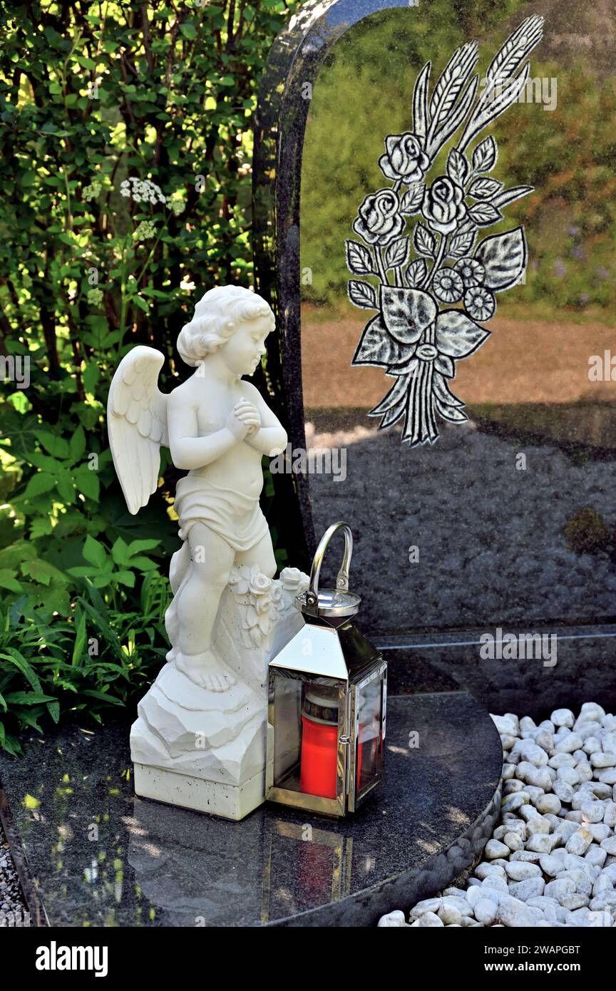 Weißer Engel und Grablaterne vor Grabstein Stockfoto