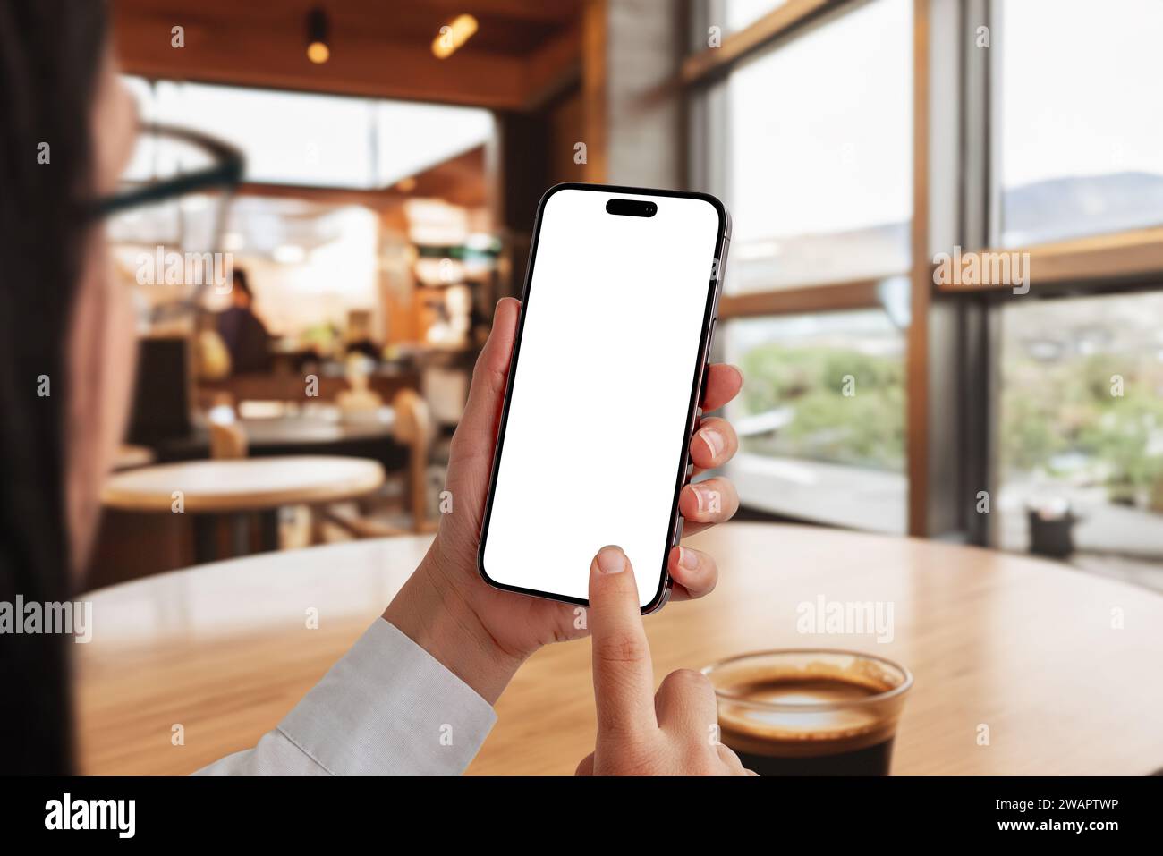 Frau in einem Café, die ein Smartphone mit einem isolierten Bildschirm für die App-Präsentation verwendet. Perfekt für die Präsentation mobiler Anwendungen in einem gemütlichen Café Stockfoto