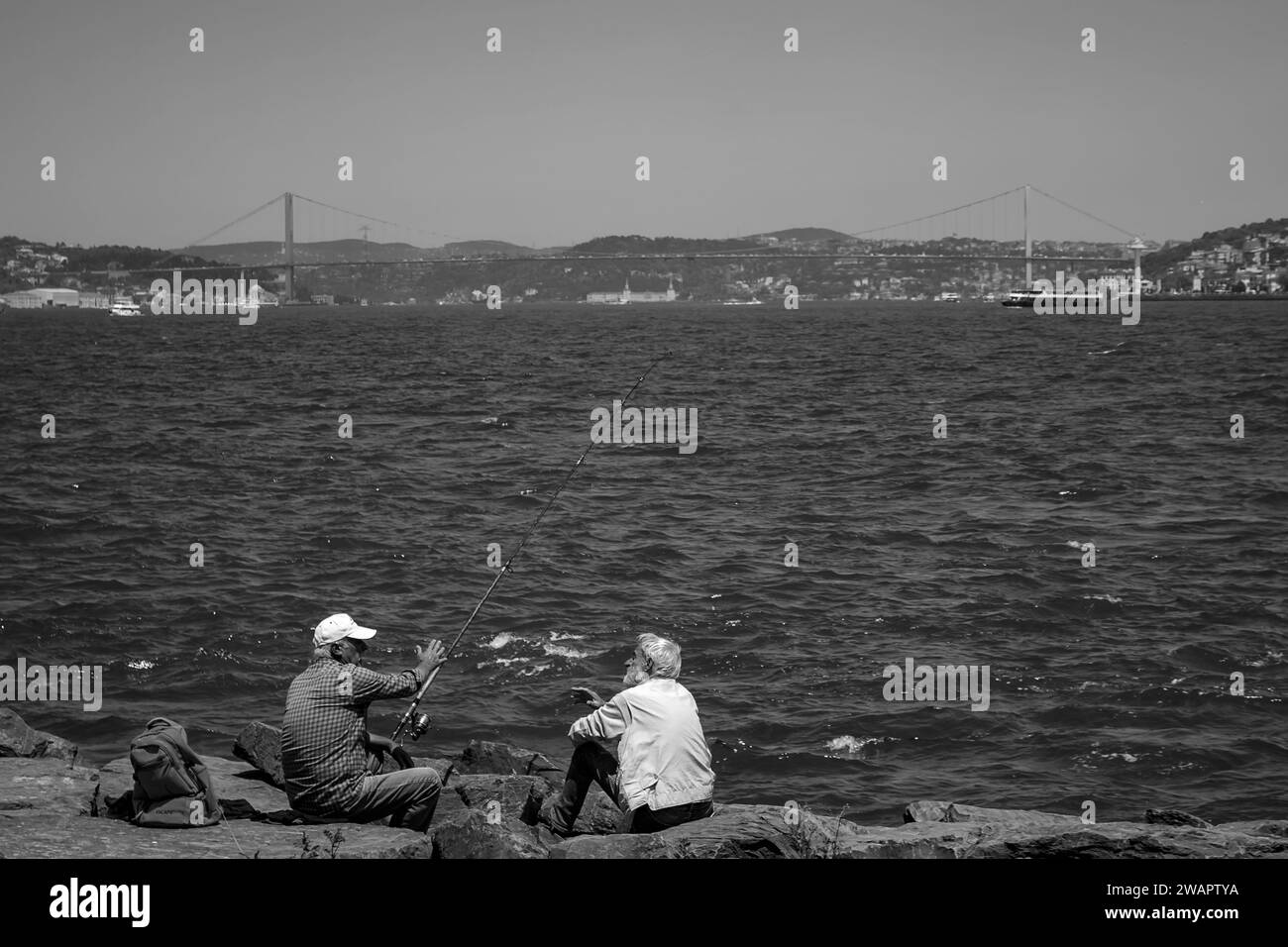 Ein paar Freunde diskutieren während eines Angelausflugs am Ufer des Bosporus Stockfoto