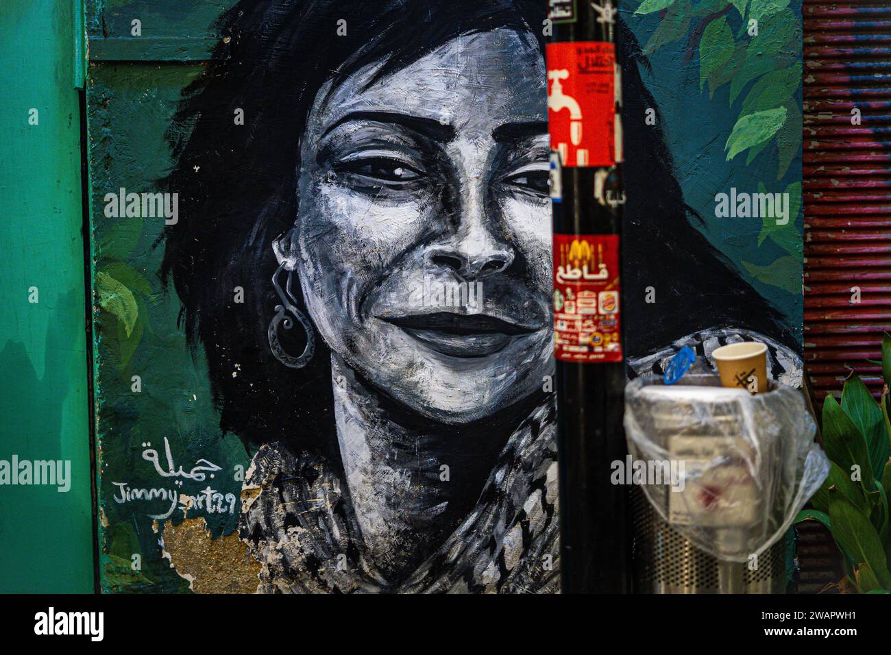 Arlington, Virginia, USA. Januar 2024. Ein Wandbild einer Palästinenserfrau mit dem Keffiyeh, einem schwarz-weißen Schal, der den palästinensischen Nationalismus und Kampf symbolisiert, ist am 5. Januar 2024 an einer Mauer im Zentrum von Amman, Jordanien, zu sehen. Das Wandgemälde ist von einem Pol mit Aufklebern geschnitten, die zum Boykott von Unternehmen und Geschäften auffordern, die Israel und die ''israelischen Besatzungstruppen'' unterstützen. Die Boykottkampagne ist Teil der globalen BDS-Bewegung, die darauf abzielt, Israel zu drängen, seine Verletzungen der palästinensischen Menschenrechte und des Völkerrechts in seinem aktuellen Krieg gegen Gaza zu beenden. (Bild: © Natascha T Stockfoto