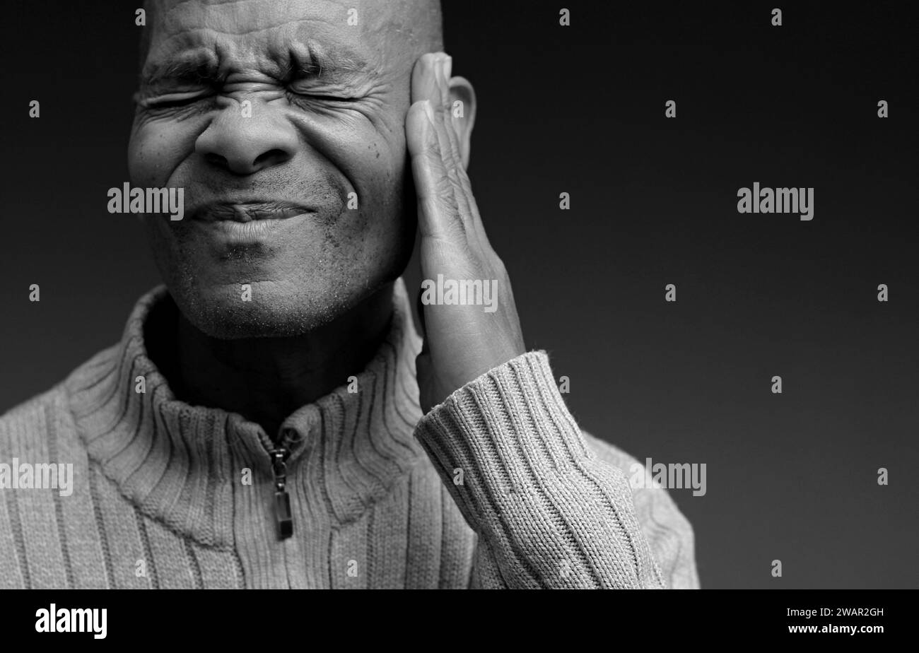 Tauber Mann, der an Taubheit und Hörverlust leidet, auf grauem schwarzem Hintergrund mit Leuten Stock-Foto Stockfoto