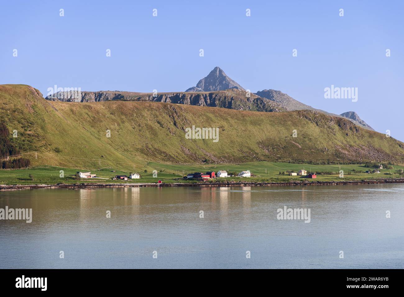 Das ruhige Wasser spiegelt die bergige Landschaft von Lofoten, Norwegen, mit farbenfrohen Häusern an der Küste wider. Offersoya, Nordland, Norwegen Stockfoto