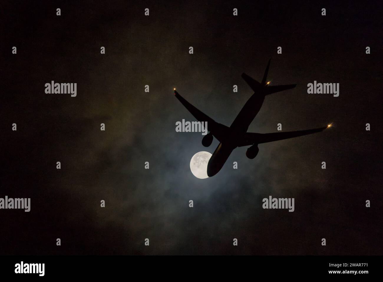Ein Flugzeug auf Nachtflug im Anflug zur Landung über den Vollmond Stockfoto