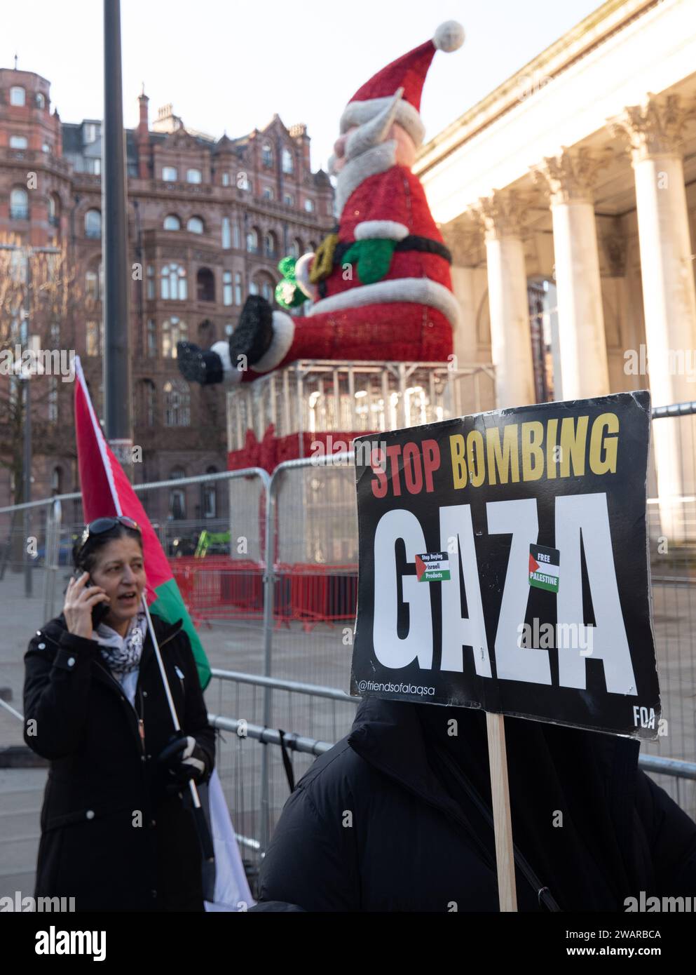 Manchester, Großbritannien. Januar 2024. Manchesters Santa ist immer noch als Demonstranten in Manchester, Großbritannien, gegen den Krieg in Gaza protestieren. Palästinensische Proteste im Zentrum von Manchester. UK. Über zweitausend Demonstranten versammelten sich auf dem Petersplatz und forderten einen Waffenstillstand. Sie marschierten dann durch das Stadtzentrum. Die Polizei bewachte Filialen, von denen die Demonstranten sagten, dass sie Verbindungen zu Israel hatten, einschließlich Barclays Bank und Starbucks Coffee. Die Demonstranten schwenkten Fahnen und trugen Plakate mit Slogans gegen den Krieg. Manchester UK. Bild: Garyroberts/worldwidefeatures.com Credit: GaryRobertsphotography/Alamy Live News Stockfoto