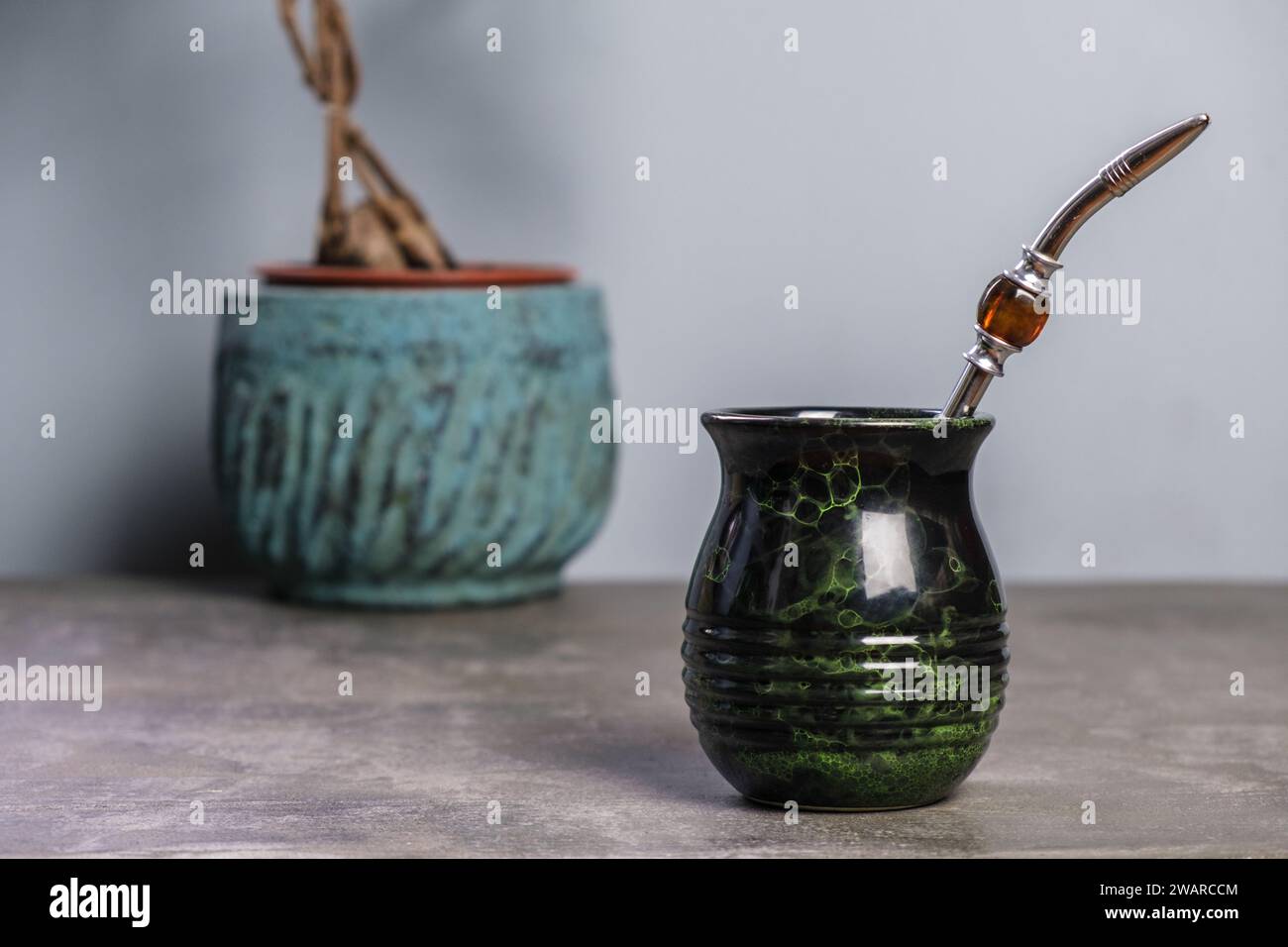 Schwarz-grüner Yerba Mate Becher mit einer Topfpflanze im Hintergrund, leerer Platz für Text Stockfoto