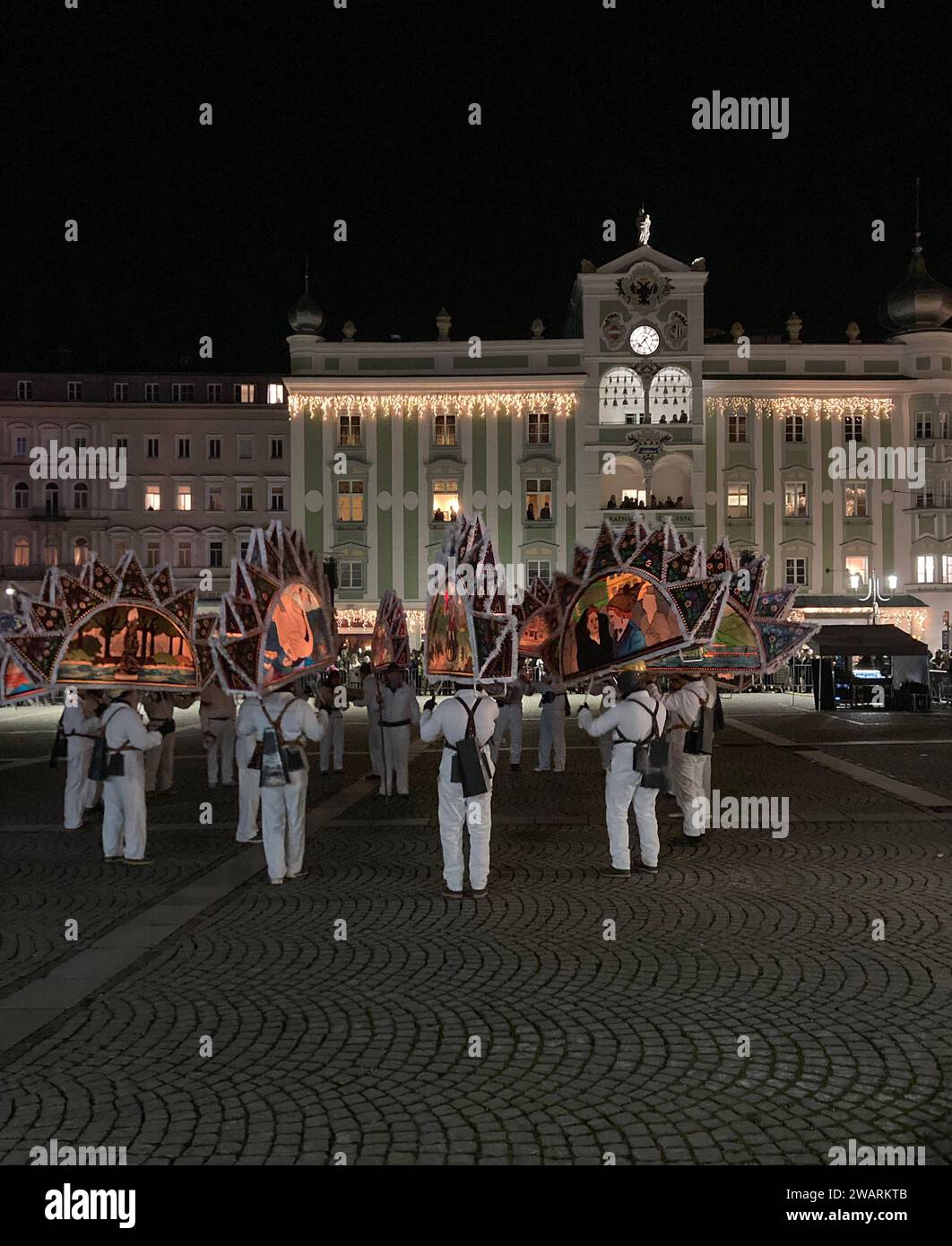 Dreikönigsingen und Glöcklerlauf am Rathausplatz in Gmunden, im oberösterreichischen Salzkammergut, am 05.01.2024. Sowohl das Dreikönigssingen als auch der Glöcklerlauf sind alte, eingeprägte Brauchtumsveranstaltungen im Salzkammergut in Österreich. Während des Glöcklerlaufs tragen junge Burschen prächtig geschmückte Laternenkappen mit meist lokalen Motiven am Kopf. Dabei wird durch laufen, springen und tanzen, mit an Gürteln der weiß Gekleideten angebrachten Glocken, entsprechend Lärm gemacht und dazu gesungen Damit treiben die Glöckler in der letzten Rauhnacht der Saison, dem 5,1. Eines jeden Stockfoto