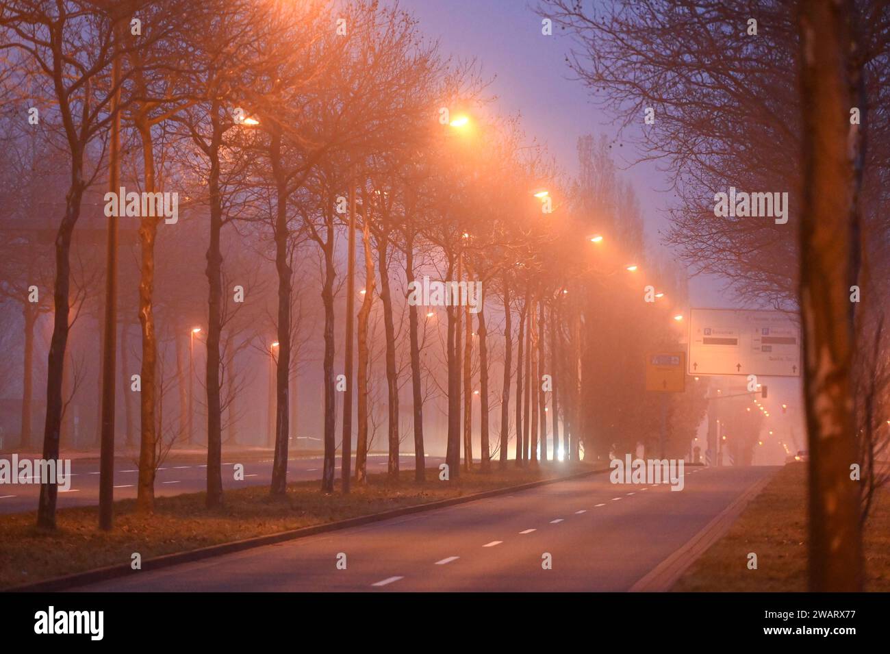 Leipzig - Nebeliger Start in den Samstagabend 06.01.2024 gegen 17 Uhr Leipzig, Messe-Allee im Foto: Eine Straße wird bei Nebel beleuchtet. In der Nacht zu Sonntag bleibt der Himmel in Sachsen bedeckt, teilweise ist es neblig - wie auch in Leipzig. Stellenweise schneit es leicht, dabei kann es glatt sein. Die Tiefstwerte liegen zwischen -2 und -4 Grad. Leipzig Sachsen Deutschland *** Leipzig Nebel Start zum Samstagabend 06 01 2024 um 17 Uhr Leipzig, Messe Allee auf dem Foto wird nachts auf Sonntag Eine Straße im Nebel beleuchtet der Himmel in Sachsen bleibt bewölkt, teilweise auch nebelig Stockfoto