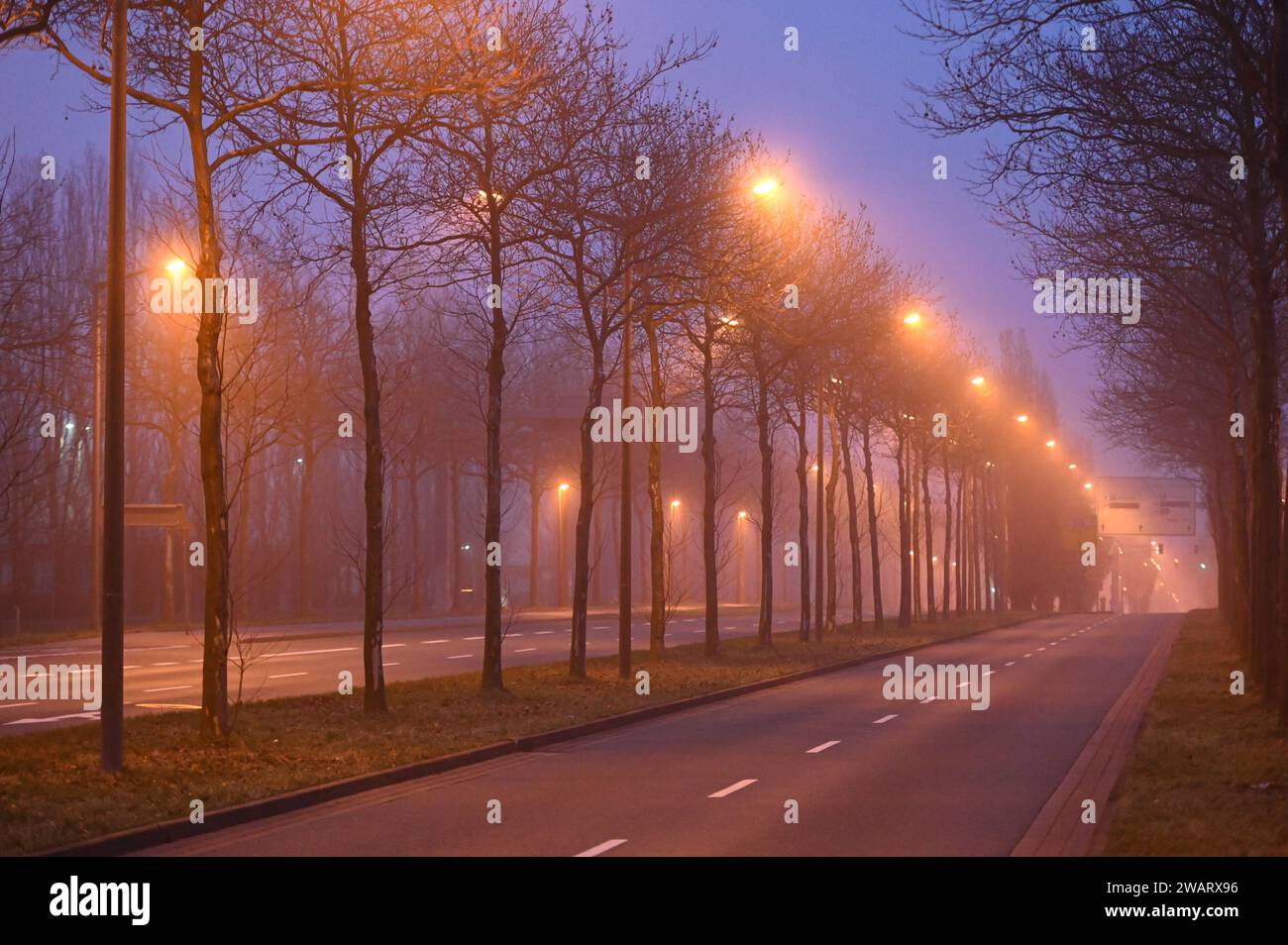 Leipzig - Nebeliger Start in den Samstagabend 06.01.2024 gegen 17 Uhr Leipzig, Messe-Allee im Foto: Eine Straße wird bei Nebel beleuchtet. In der Nacht zu Sonntag bleibt der Himmel in Sachsen bedeckt, teilweise ist es neblig - wie auch in Leipzig. Stellenweise schneit es leicht, dabei kann es glatt sein. Die Tiefstwerte liegen zwischen -2 und -4 Grad. Leipzig Sachsen Deutschland *** Leipzig Nebel Start zum Samstagabend 06 01 2024 um 17 Uhr Leipzig, Messe Allee auf dem Foto wird nachts auf Sonntag Eine Straße im Nebel beleuchtet der Himmel in Sachsen bleibt bewölkt, teilweise auch nebelig Stockfoto