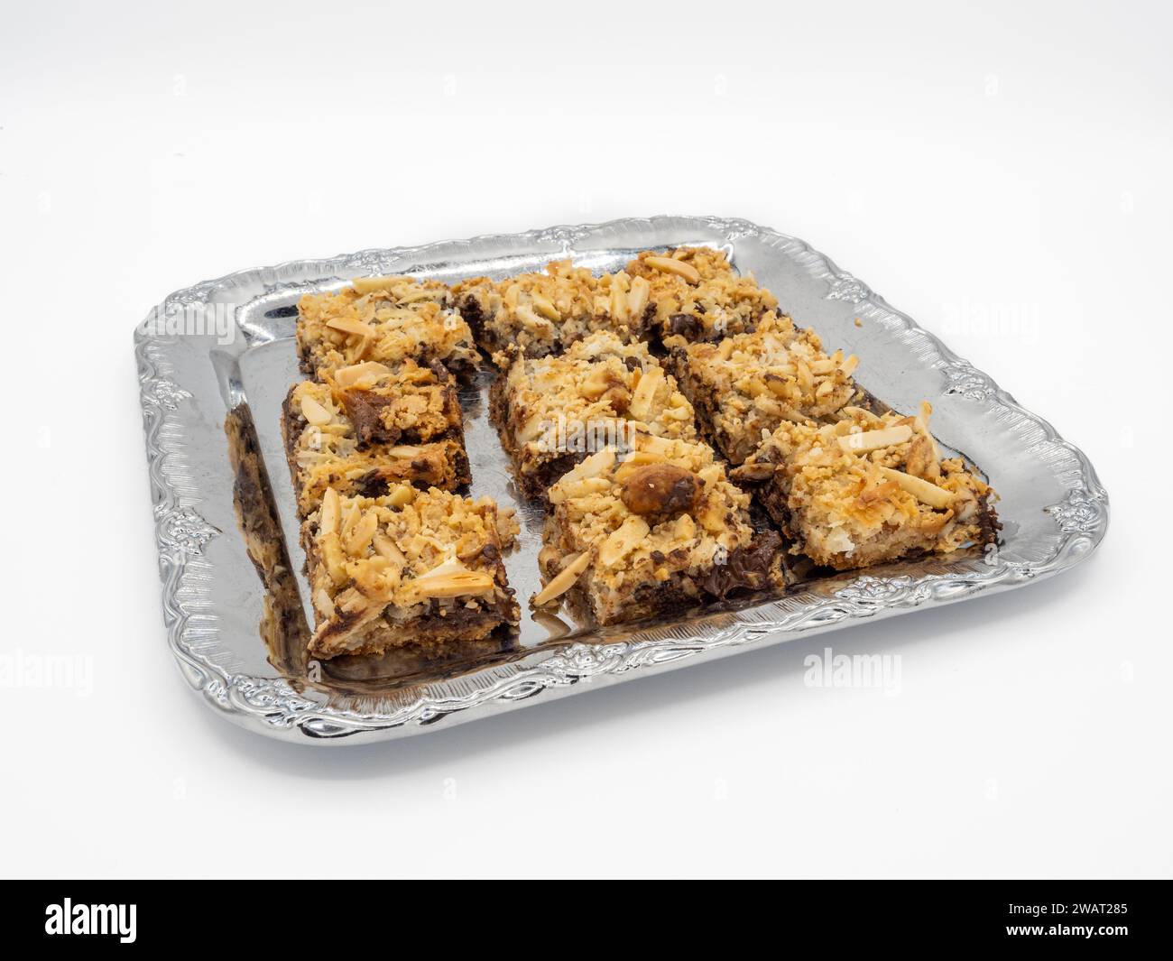 Eine köstliche Auswahl an Brownies mit goldenen Mandelflocken, bereit, im Mund zu schmelzen. Präsentiert auf Metallplatte isoliert auf weißem Hintergrund. Stockfoto