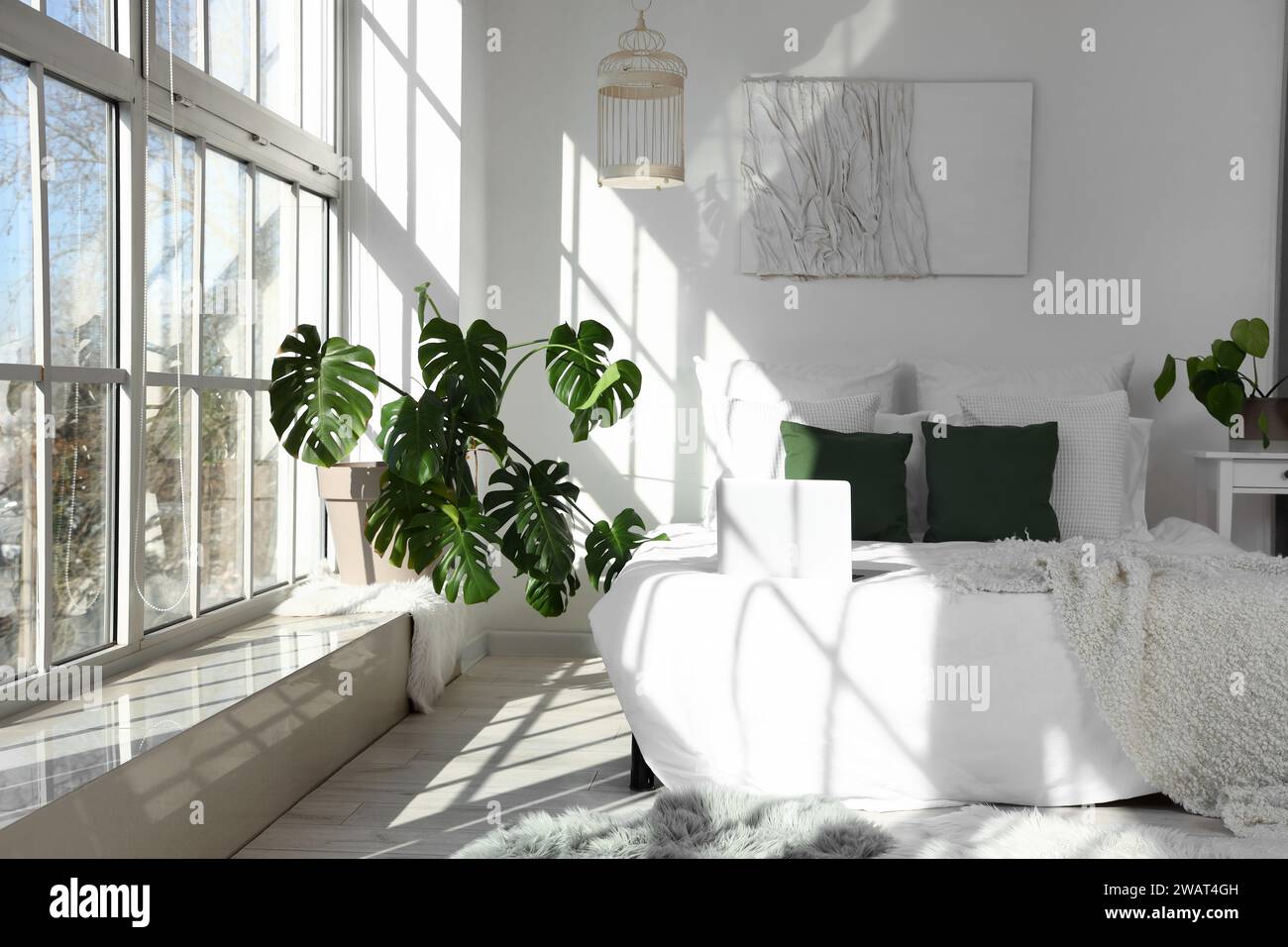 Helles Schlafzimmer mit Monstera-Zimmerpflanze und Bett Stockfotografie -  Alamy