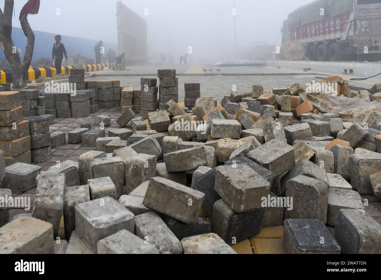 Ayodhya, Indien. Dezember 2023. An einem nebligen Morgen vor dem Besuch des indischen Premierministers Narendra Modi in Ayodhya werden Pflastersteine über einem neu gebauten Pflaster gelegt. Ramnagari Ayodhya, einst bekannt für seine engen Gassen und verfallenen Straßen, macht stetige Fortschritte: Alle Straßen und Gebäude, die zum RAM Janmabhoomi führen, werden erweitert und renoviert, um ein reibungsloses Reisen zu ermöglichen. (Credit Image: © Biplov Bhuyan/SOPA Images via ZUMA Press Wire) NUR REDAKTIONELLE VERWENDUNG! Nicht für kommerzielle ZWECKE! Stockfoto