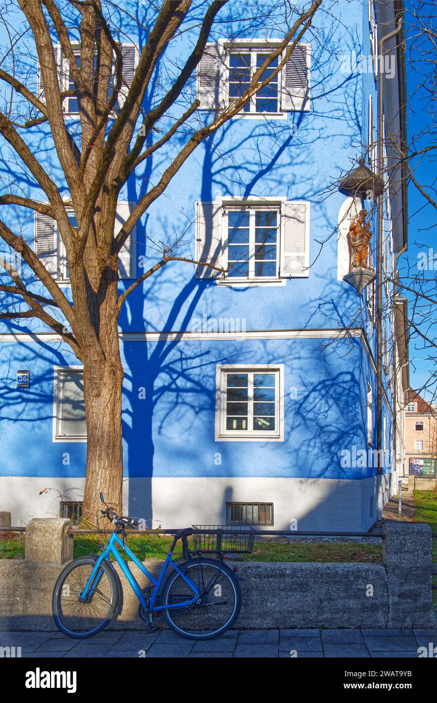 Blaues Fahrrad vor einem blauen Haus mit einem Ornament. Licht und Schatten Stockfoto