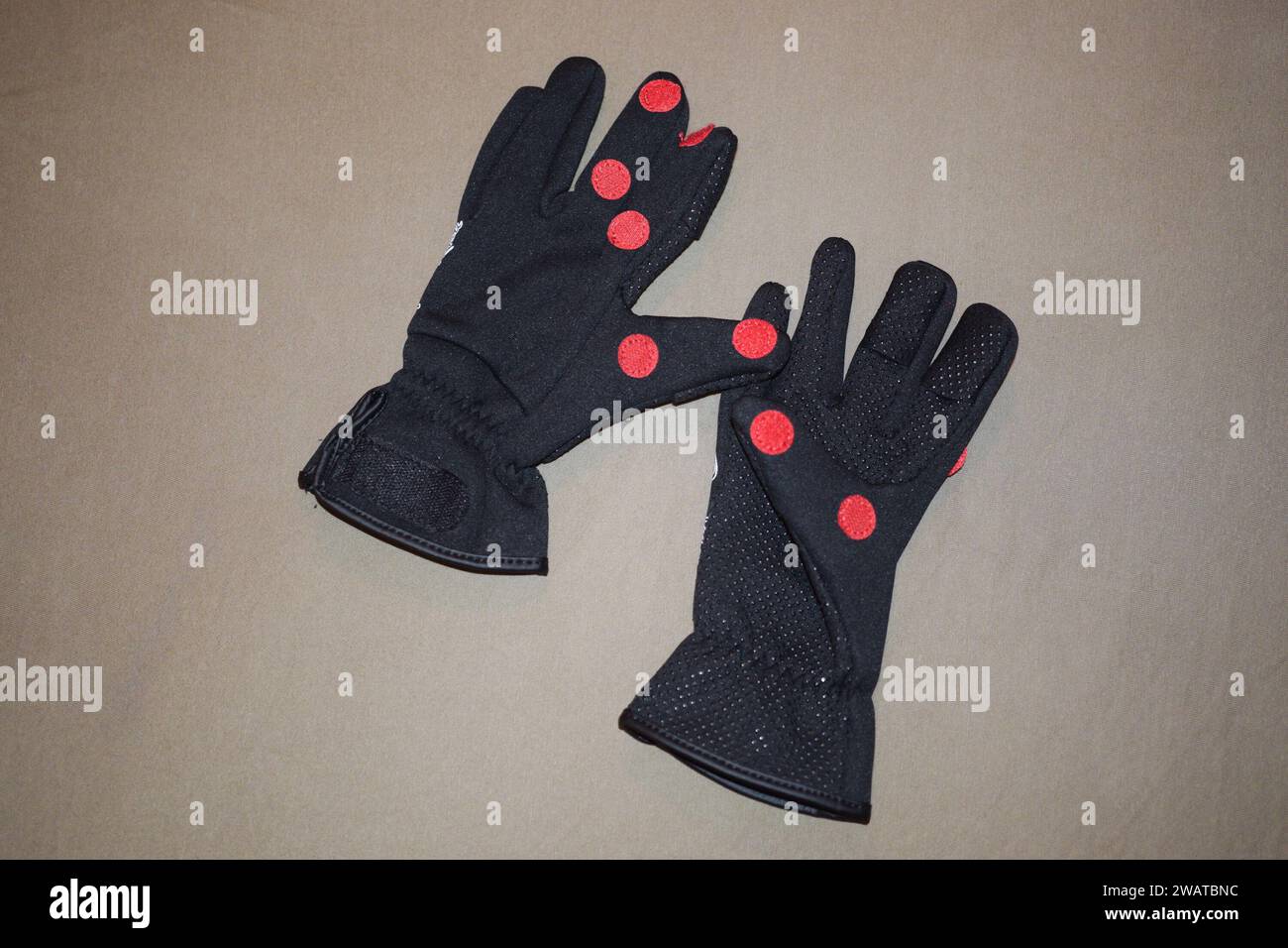 Schwarze Eisangel-Handschuhe mit umklappbaren Fingerspitzen und rotem Klebeband. Stockfoto