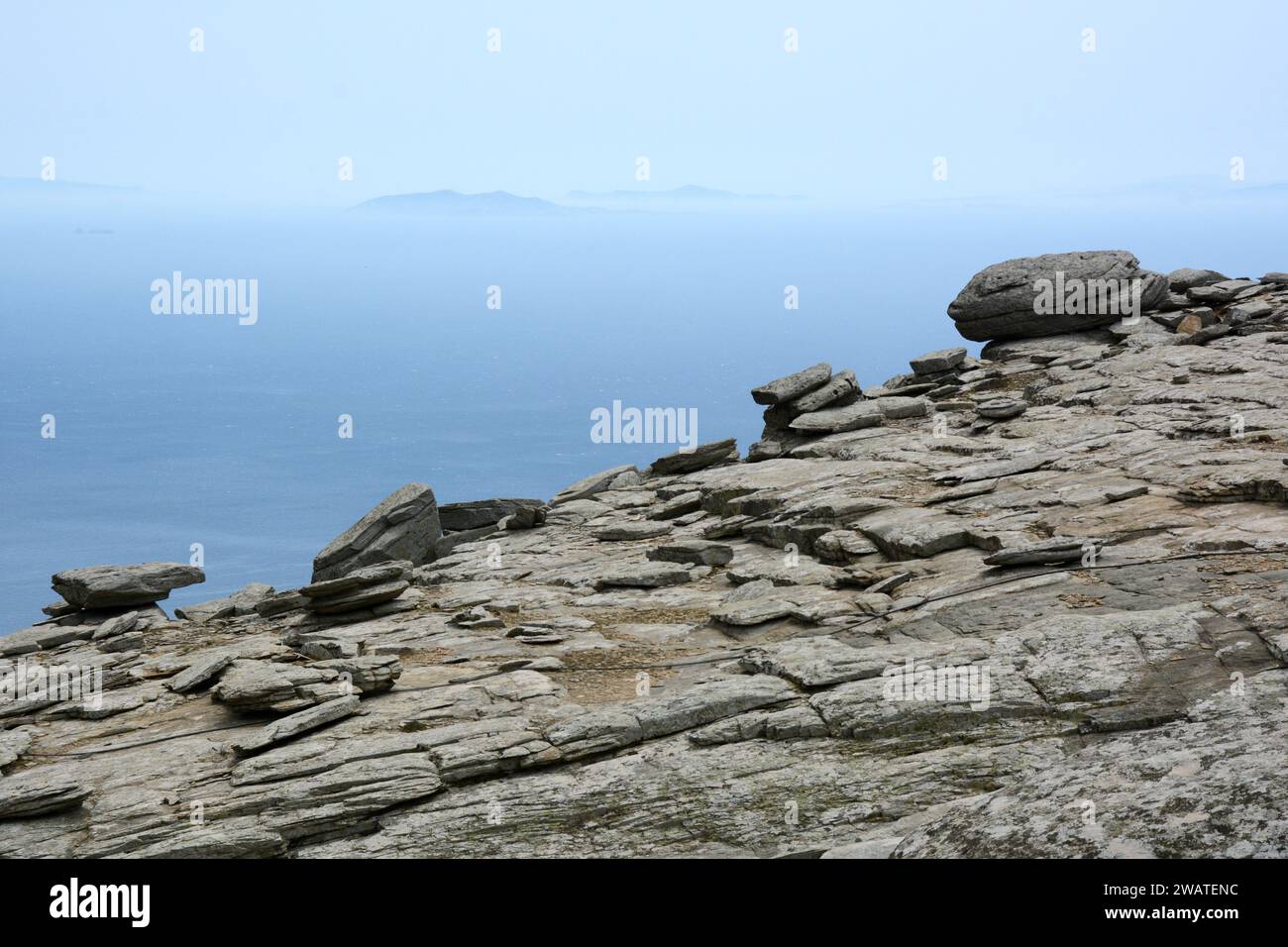 Ein steiler, felsiger Berg und Klippen, die über der Ägäis thronen, an der Südküste der griechischen Insel Ikaria, in der Nähe von Karkinagri, Griechenland. Stockfoto