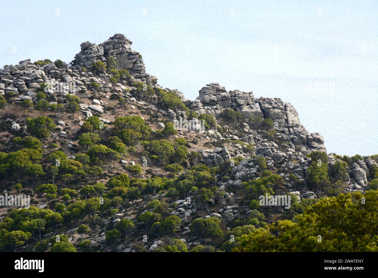 Ein steiler, felsiger Berg und Klippen, die über der Ägäis thronen, an der Südküste der griechischen Insel Ikaria, in der Nähe von Karkinagri, Griechenland. Stockfoto