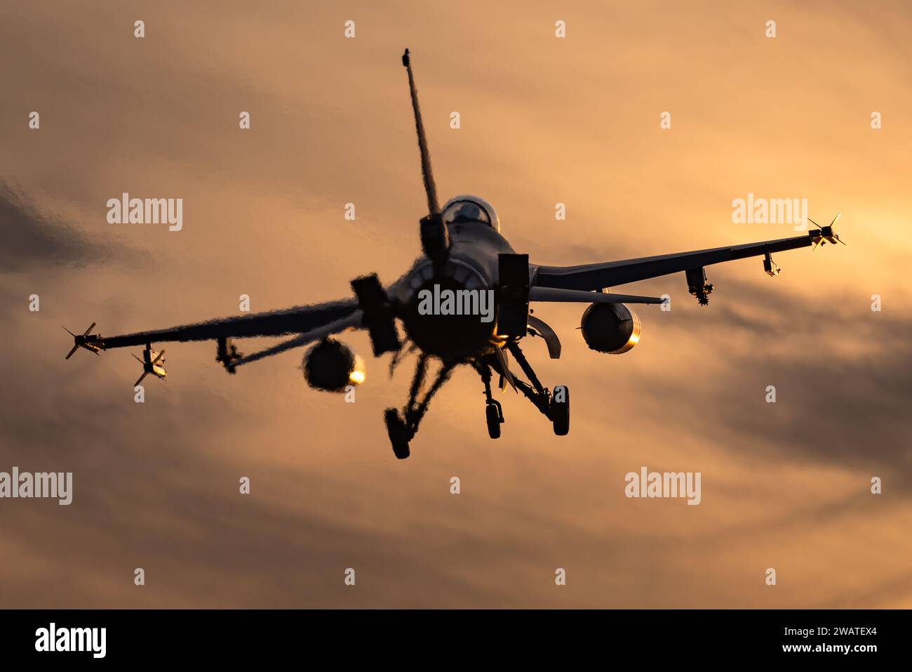 Ein F-16 Kampfflugzeug ist bereit, bei einem wunderschönen Sonnenuntergang auf einem Luftwaffenstützpunkt zu landen. Stockfoto