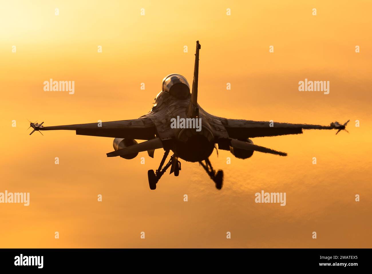 Ein F-16 Kampfflugzeug ist bereit, bei einem wunderschönen Sonnenuntergang auf einem Luftwaffenstützpunkt zu landen. Stockfoto