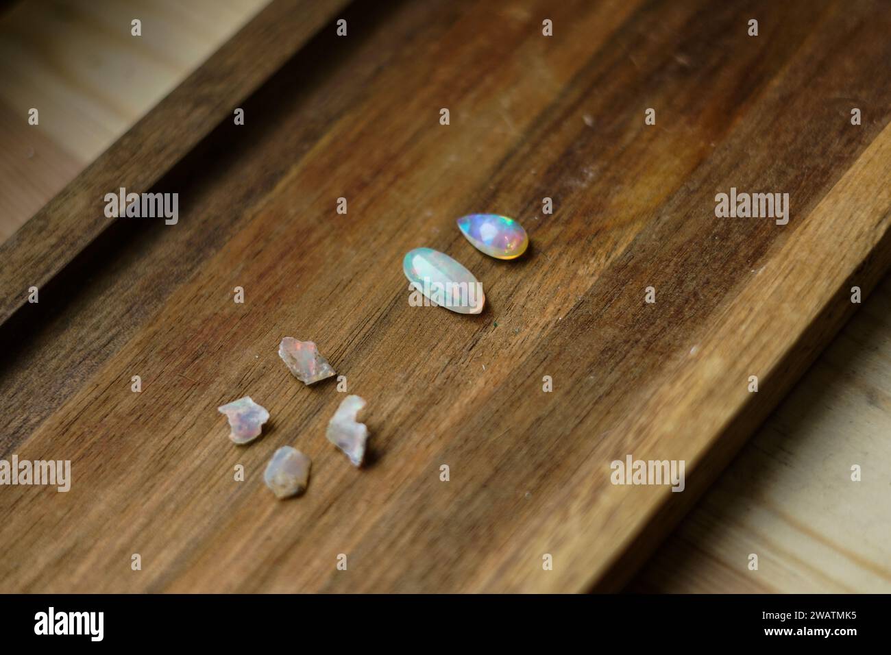 Grobe und geschliffene Opalsteine auf hölzernem Hintergrund. Stockfoto