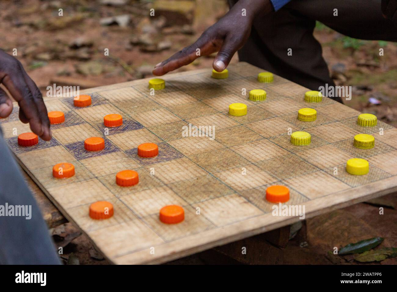 Ugandische Männer spielen Entwürfe (Checker) mit Kunststoff Flasche Kappen als Stücke dienen. Stockfoto