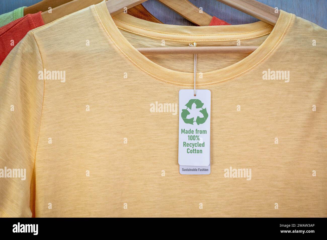 T-Shirt mit dem Symbol „Recycle Clothes“ auf dem Etikett mit Text „Sustainable Fashion“ aus 100 % recycelter Baumwolle. Nachhaltige Kreismode und ethisches Shopping Stockfoto