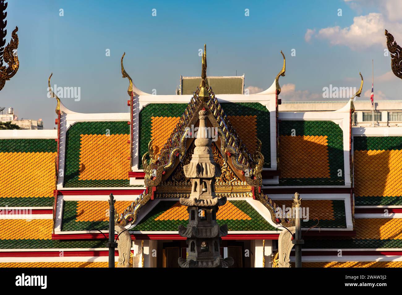 Wat Suthat in Bangkok, Thailand. Der königliche Tempel wurde 1807 erbaut. Bunte Dachziegel, kunstvoll verzierte Golddetails. Blauer Himmel. Stockfoto