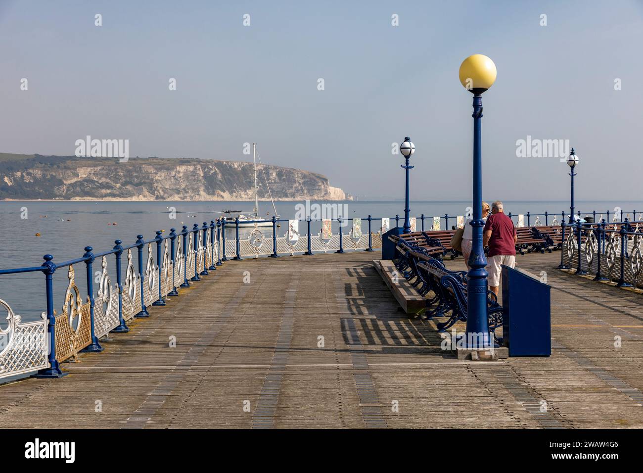 Swanage Pier, älteres Paar spazieren auf dem Pier mit Blick auf die juraküste und Ballard Cliff, Cornwall, England, UK, 2023 Stockfoto