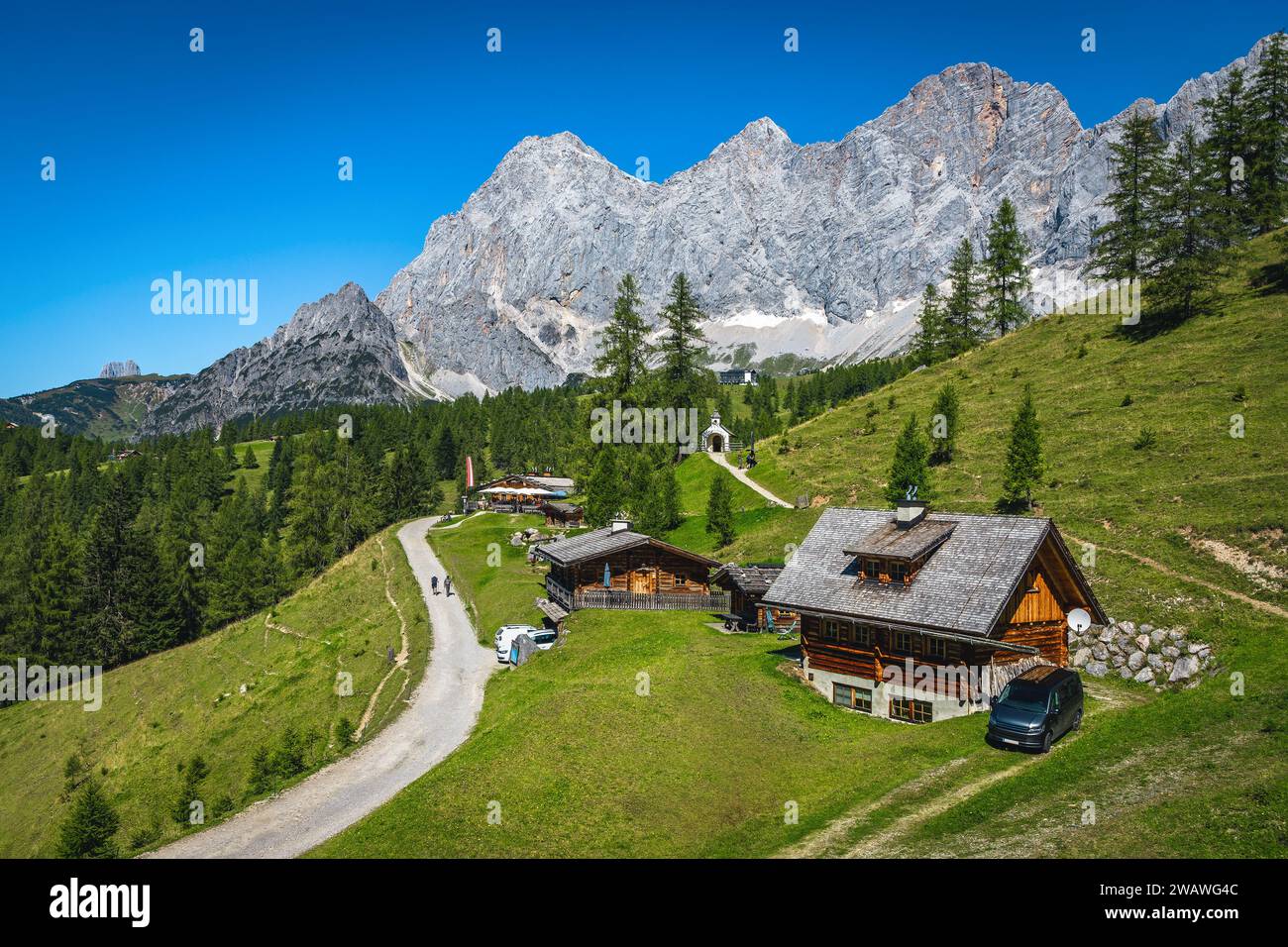 Berühmter Wander- und Reiseort, ländliche Holzhäuser auf den grünen Almwiesen. Malerische Dachsteinberge im Hintergrund, Ramsau am Dachstein Stockfoto