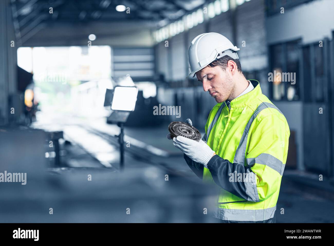 Professioneller Ingenieur kaukasischer männlicher Inspektor Advance Technology Maschinenbau präzises Getriebeteil mit hoher Detailaufmerksamkeit blauer Farbton Stockfoto