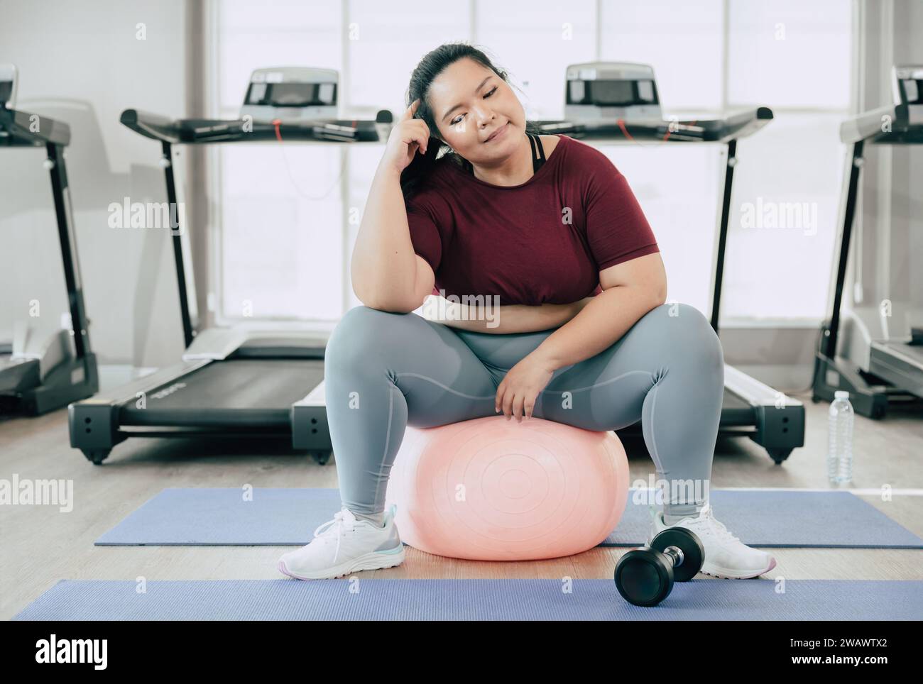 Frauen in Übergröße denken Fragestellung, asiatische fette weibliche, die im Fitness-Studio des Sportclubs sitzt Stockfoto