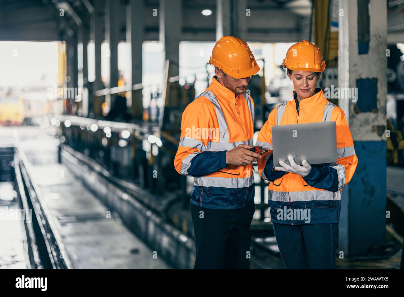 Team für Sicherheitsingenieure, die mit der Inspektion von Laptops in einer Baufabrik für Schwerindustrie zusammenarbeiten. Stockfoto