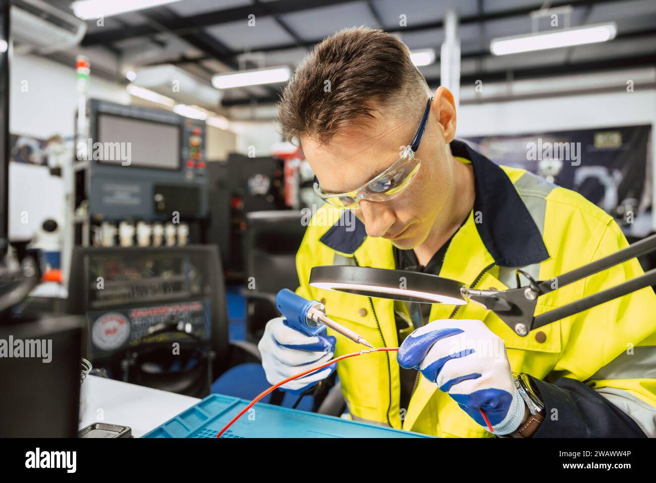Elektriker Techniker kaukasischer Mann mit heißem Lötkolben, um Elektrizitätsdraht zu verbinden, reparieren Sie Stromkabel mit Lötzinn und lea Stockfoto