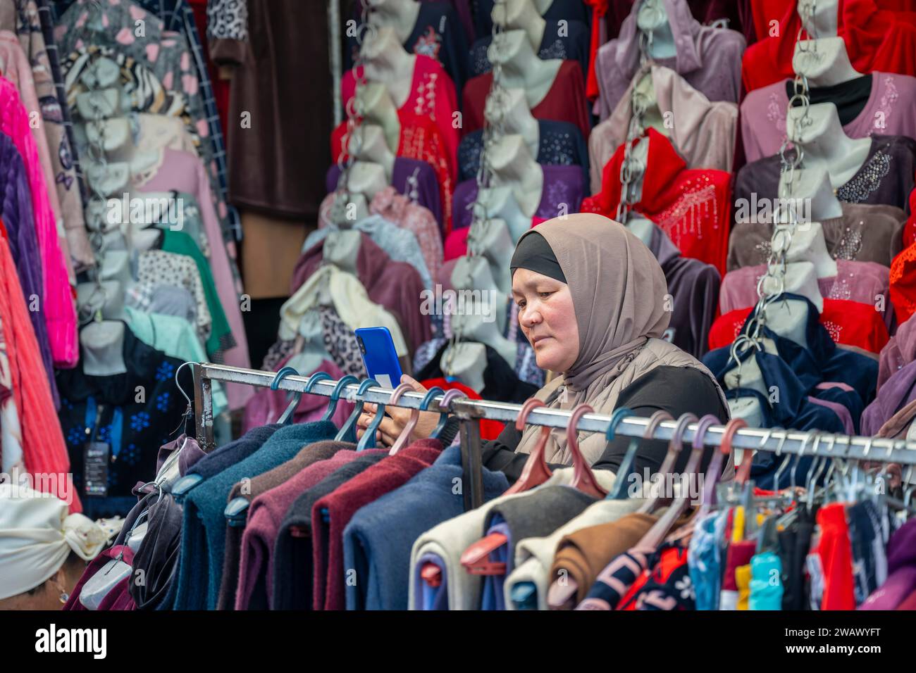 Frau, die Kleidung kauft, Marktstand auf dem Osh Bazaar, Bischkek, Kirgisistan Stockfoto