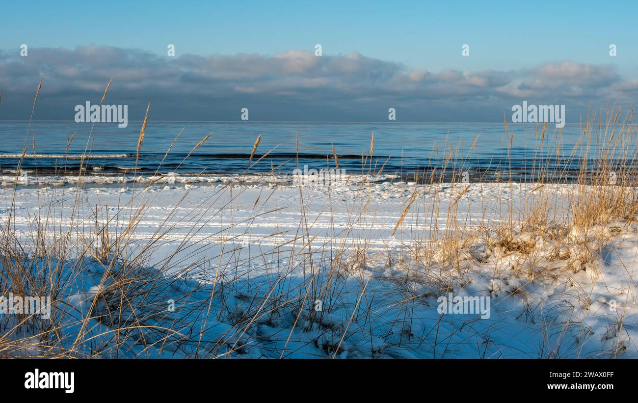 Eine ruhige verbindung: Das eisige Meer trifft auf das goldene Flüstern der Winterdämmerung an verschneiten Küsten. Stockfoto