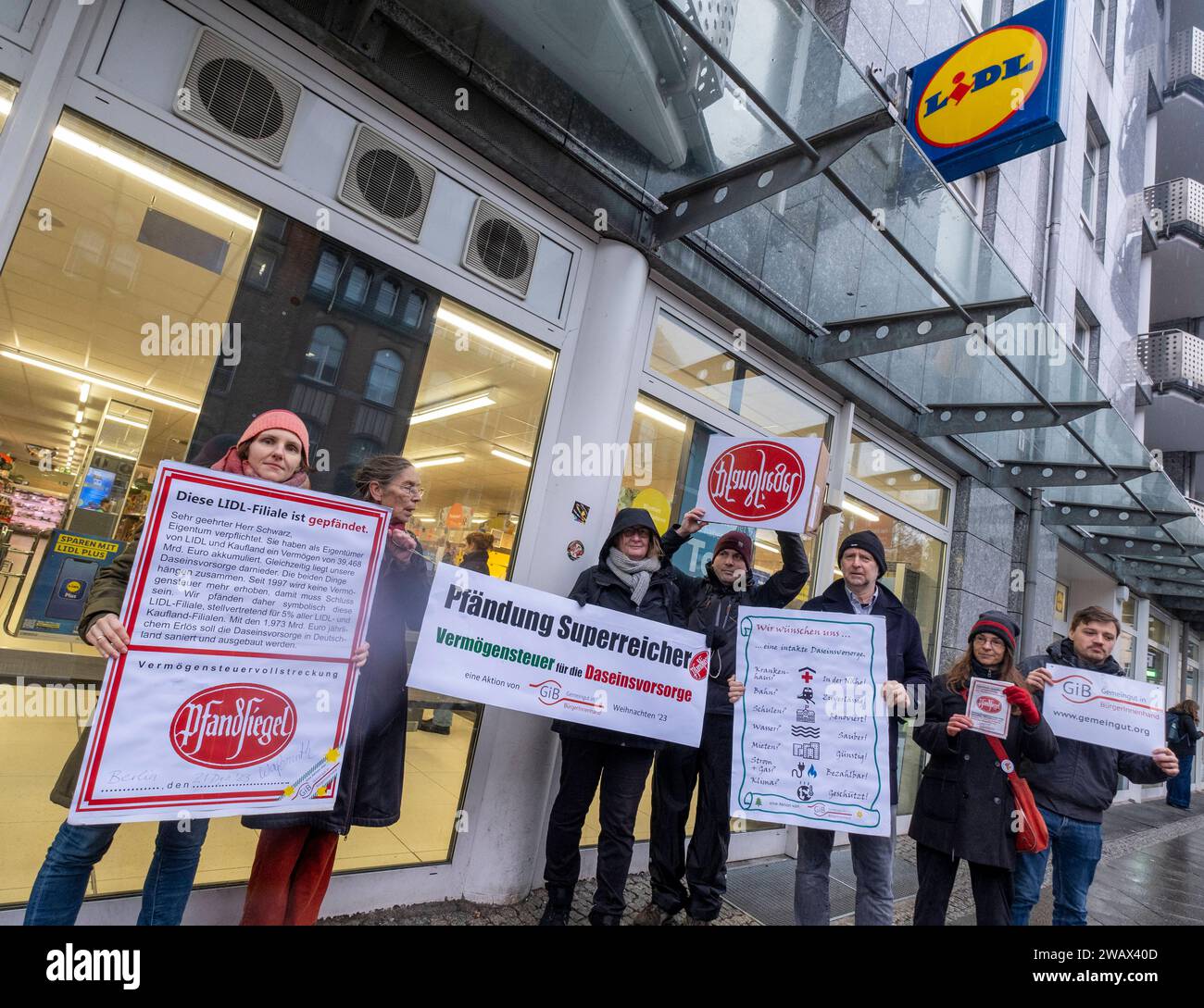 Symbolische Pfändungen von Superreichen Deutschland, Berlin, 21.12.2023, Aktion von Gemeingut in BürgerInnenhand giB, Aktionen vor Filialen von LIDL, Aldi und BMW, hier eine Lidl Filiale in der Luisenstraße / Berlin-Mitte, Aktivisten drücken ein großes Pfandsiegel auf eine Tür der Lidl-Filiale, Carl Waßmuth, Sprecher von Gemeingut: Superreiche wie LIDL-Eigentümer Dieter Schwarz zahlen nur winzige Steuersätze, Â *** symbolische Beschlagnahmen des superreichen Deutschland, Berlin, 21 12 2023, Aktion Gemeingut in BürgerInnenhand giB , Aktionen vor Zweigen von LIDL, Aldi und BMW, hier eine Lidl-Niederlassung in L Stockfoto